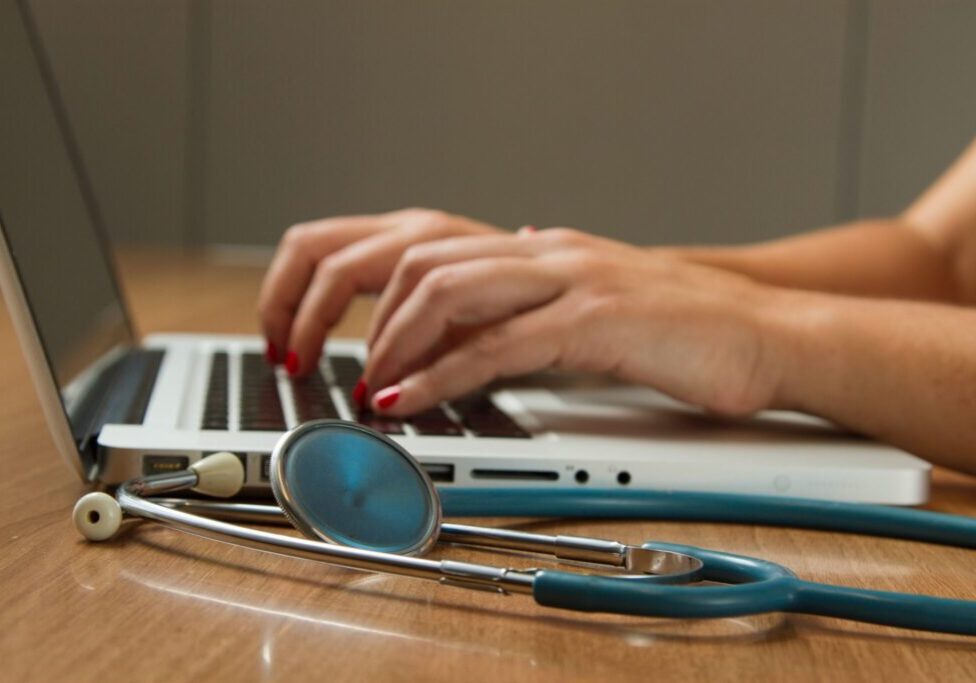 Dialysis plan choice coverage comparison A person typing on a laptop next to stethoscope.