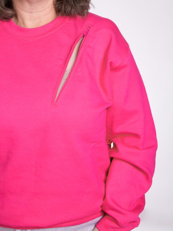 A close up of the arm and shoulder of a person wearing a pink sweatshirt.